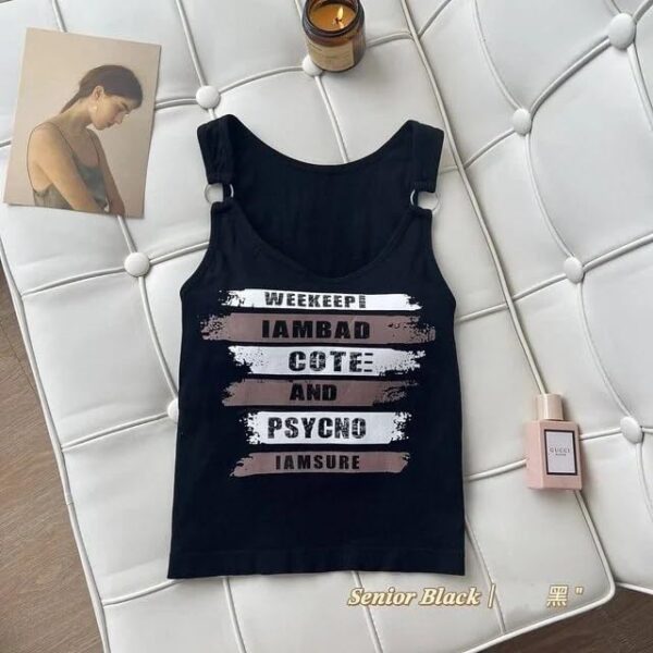 Black women's sleeveless halter neck crop top with printed grunge text, metal ring straps, and a fitted silhouette.