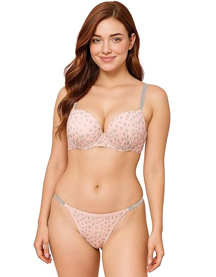 Woman wearing a light pink printed bra and thong-style panty set with glittery straps and soft finish.