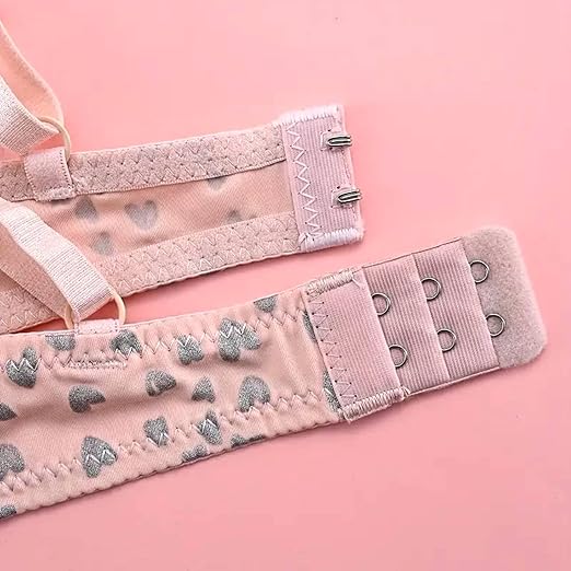 Woman wearing a light pink printed bra and thong-style panty set with glittery straps and soft finish.